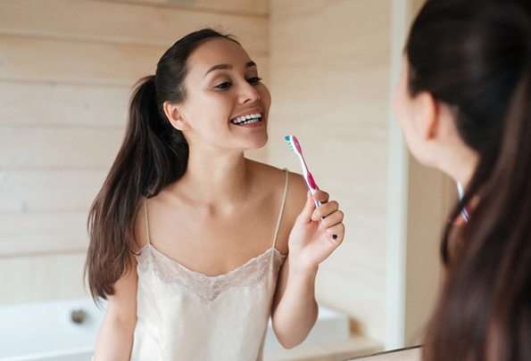 Woman brushing teeth to maintain teeth whitening in Everett