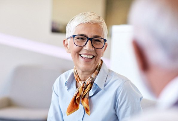 Senior woman with glasses smiling with All-on-4 dental implants in Everett, WA
