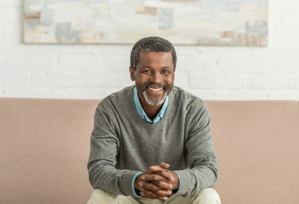 Senior man with All-on-4 dental implants in Everett, WA sitting on couch smiling