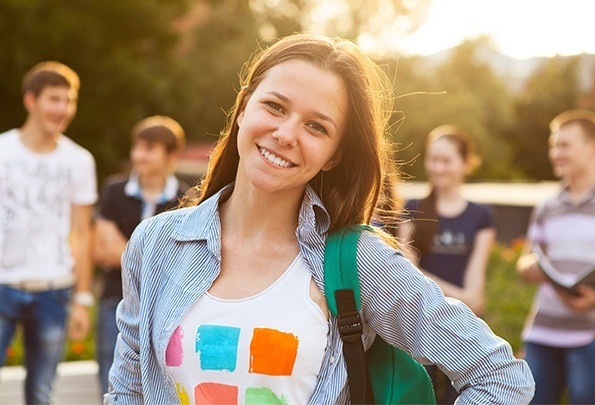 Young woman smiling outdoors after children's dentistry visit