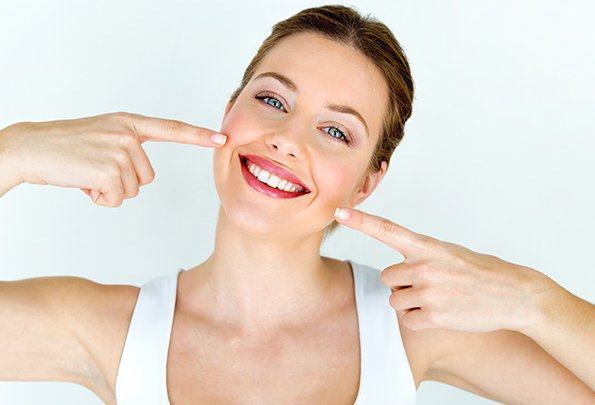 Woman pointing to her teeth after smile makeover