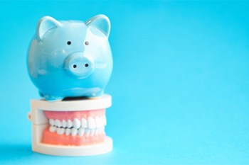 A blue piggy bank and model jaw mockup against a light blue background