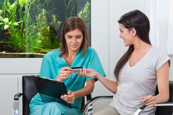 A woman paying the cost of cosmetic dentistry with a credit card