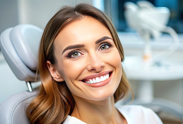 A young woman smiling in the dentist’s chair after receiving dental crowns in Everett