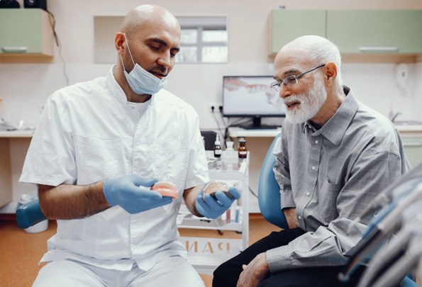 An older man talking with his dentist about denture candidacy 