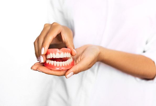Female dentist holding a pair of dentures