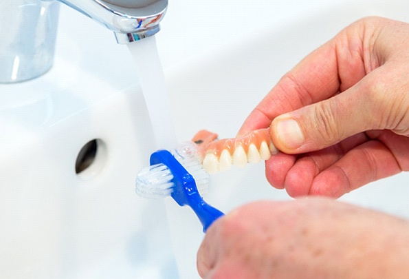 Rinsing dentures and toothbrush under the sink