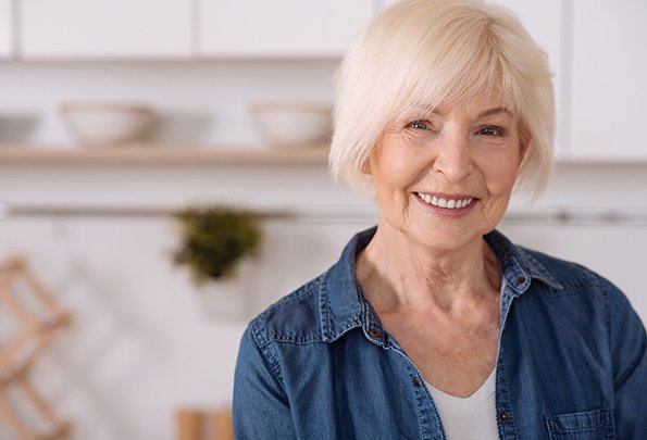 Senior woman in denim jacket smiling with dentures in Everett, WA