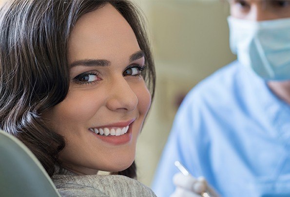 Smiling woman at dental checkup to prevent dental emergencies