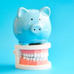 blue piggy bank sitting on top of dentures  