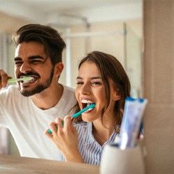 A man and woman brushing their teeth