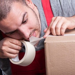 A man tearing tape with his teeth