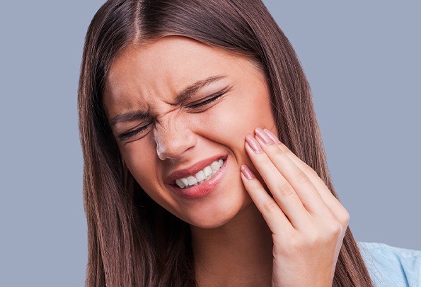 Grimacing woman holding cheek before tooth extraction