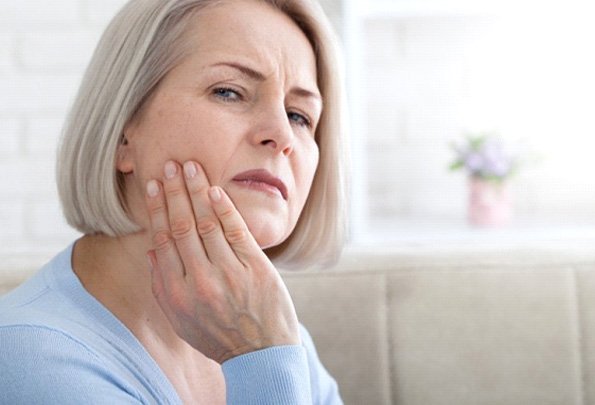 a woman touching her cheek due to tooth pain