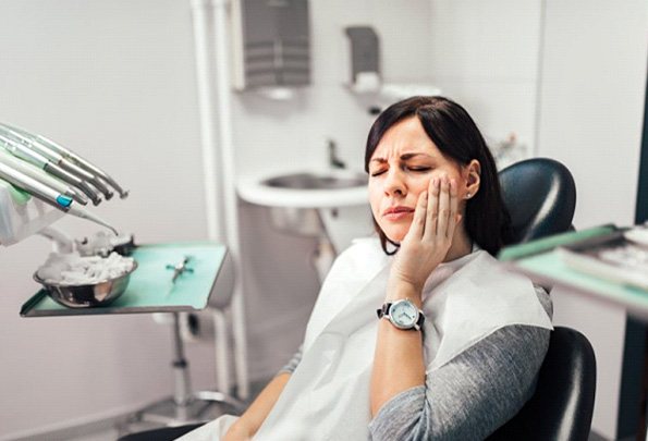 a patient touching her cheek due to tooth pain