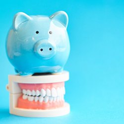 blue piggy bank sitting on top of a set of full dentures 