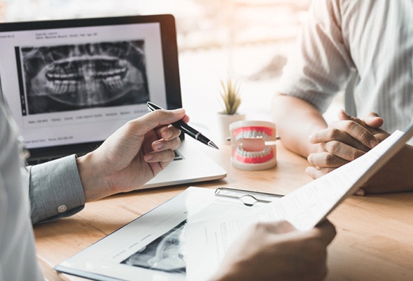 A dentist explains to a patient how full mouth dental implants work and whether they are a qualified candidate