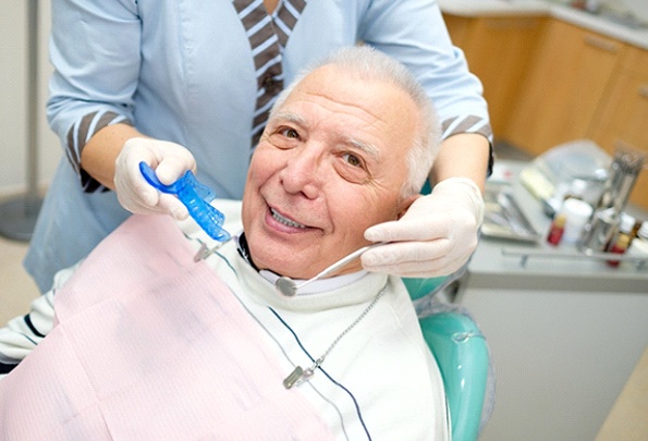 Older man smiling while visiting implant dentist in Everett