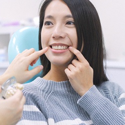 Woman smiling and pointing to teeth during consultation