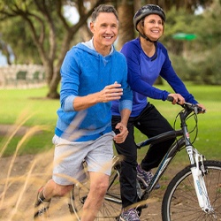 Middle-aged man and woman smiling while exercising outside