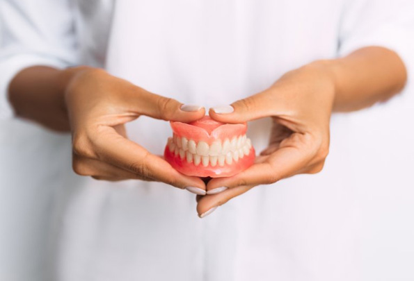Dentist holding full set of dentures in Everett 