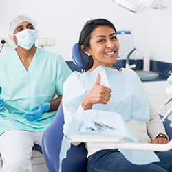 Smiling patient giving thumbs up while sitting in treatment chair