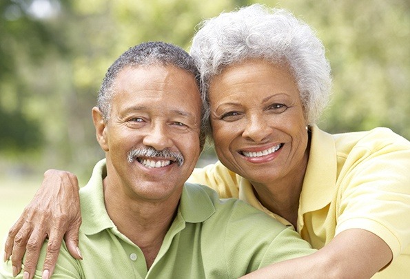 Smiling older man and woman outdoors after restorative dentistry