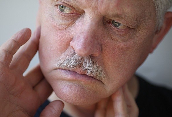 Older man in need of root canal holding his jaw joints
