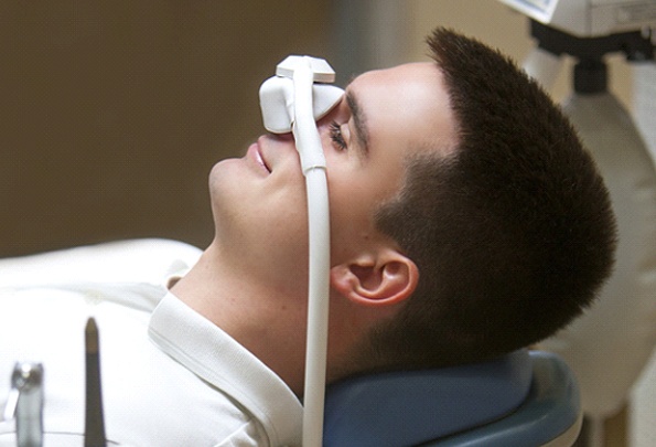 A young man lying back in the dentist’s chair wearing a mask over his nose to receive nitrous oxide in Everett