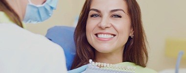 Woman in dental chair smiling after cosmetic dentistry