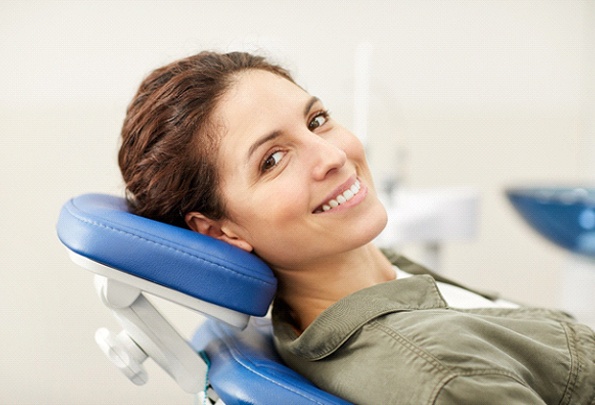 Woman in dentist’s chair smiling after TMJ treatment