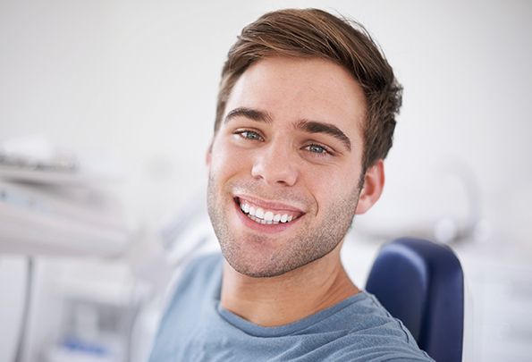Smiling young man in dental chair after wisdom tooth extraction