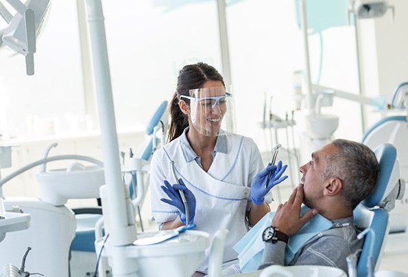 Closeup of person holding jaw in pain before wisdom tooth extraction