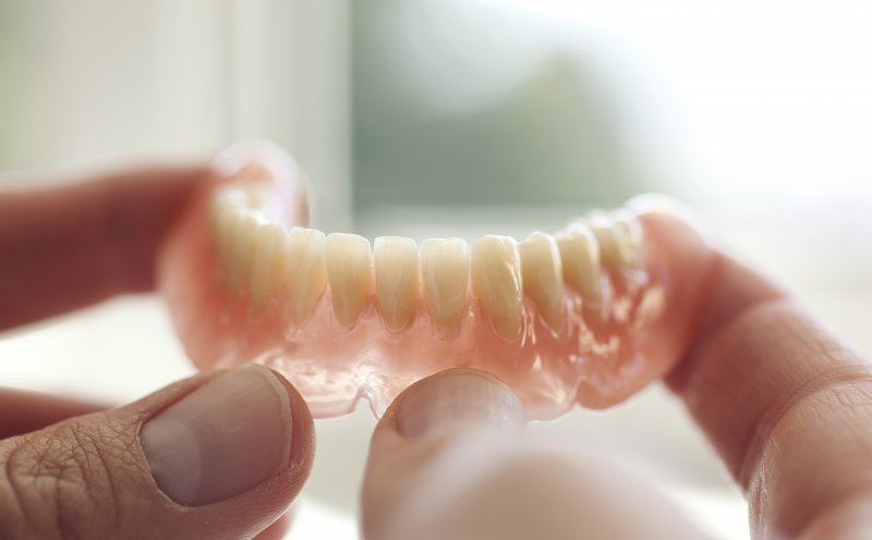 a person holding a lower full denture