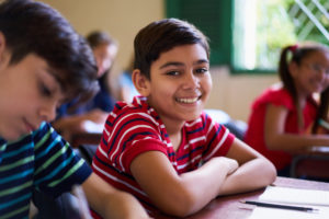 Happy boy smiling and sitting at desk