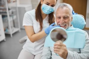 Man smiling at the dentist after receiving dental implants.