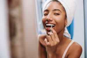 Woman looking in mirror to floss her teeth