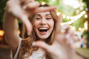 Woman smiling through square made by her fingers.